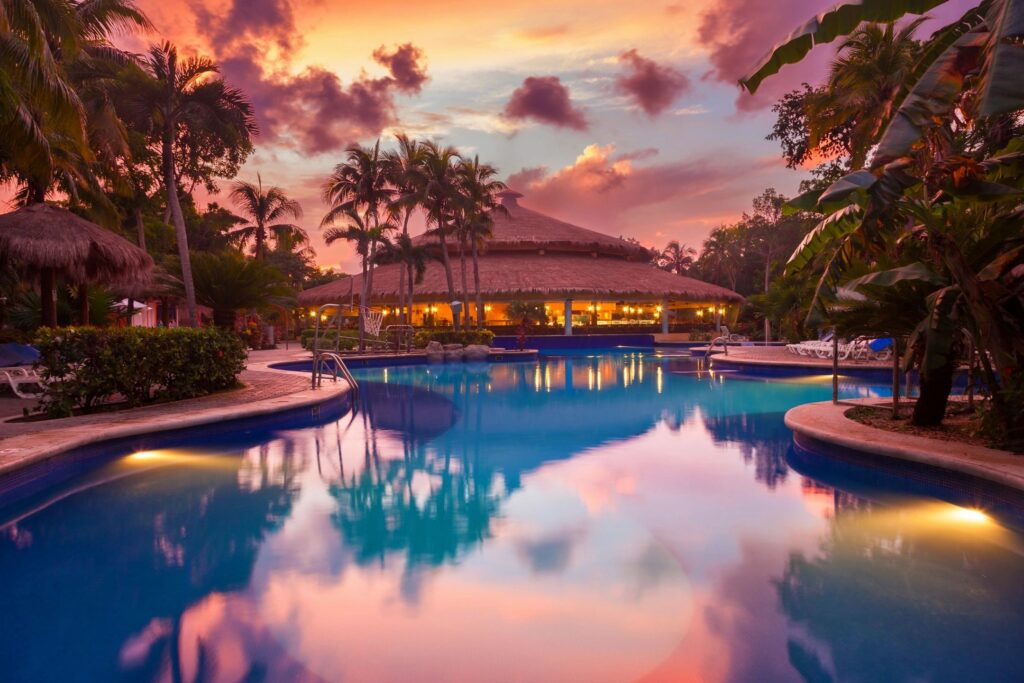 Resort pool reflecting colorful sunset sky